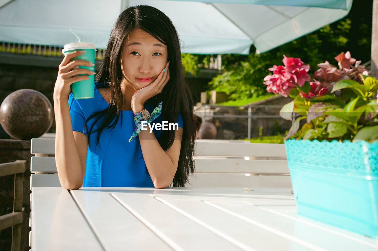 Woman having coffee while sitting at outdoor cafe