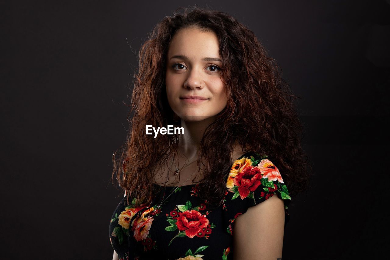 Portrait of smiling young woman against black background. never too late. 