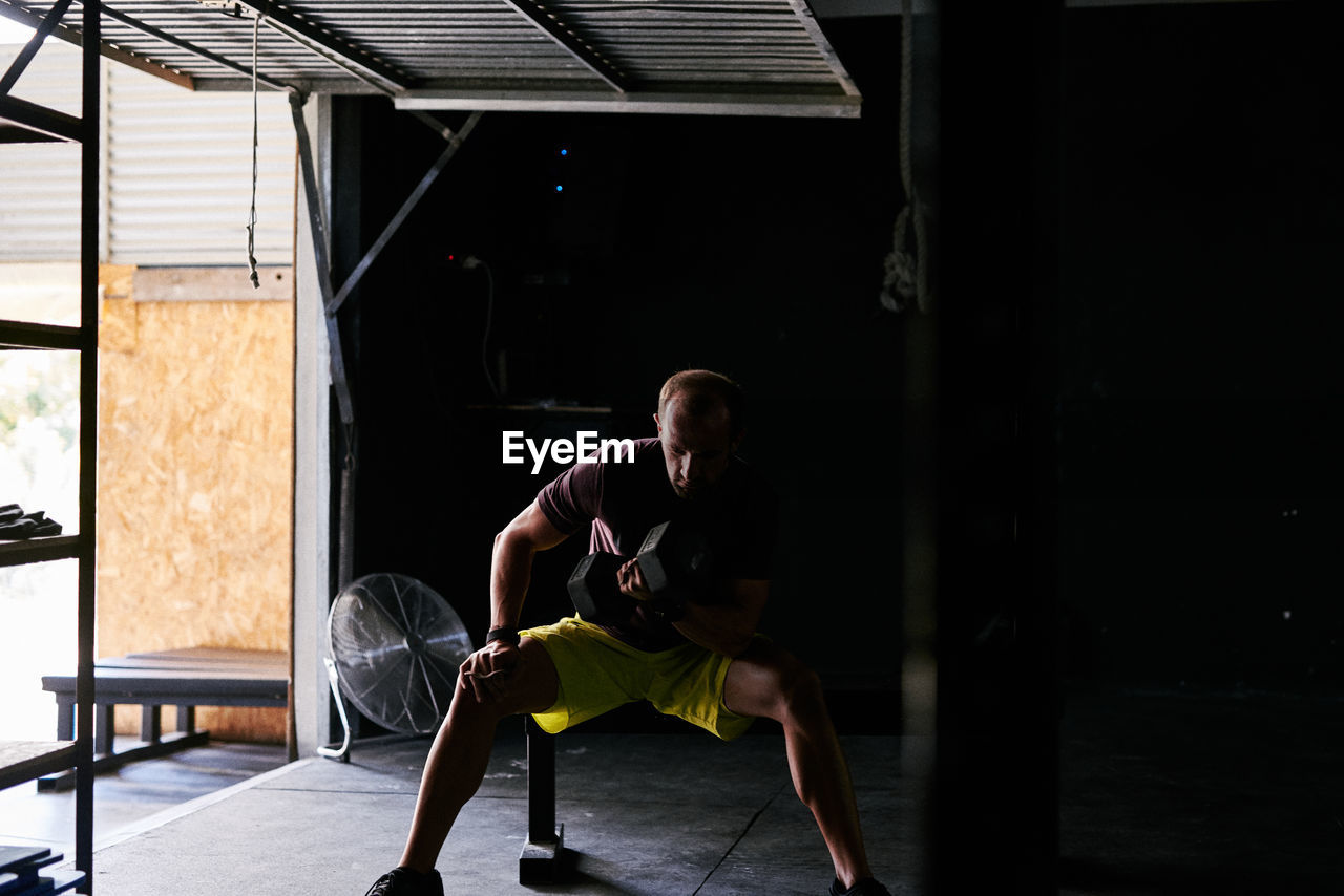 Young man working out with dumbells in a garage