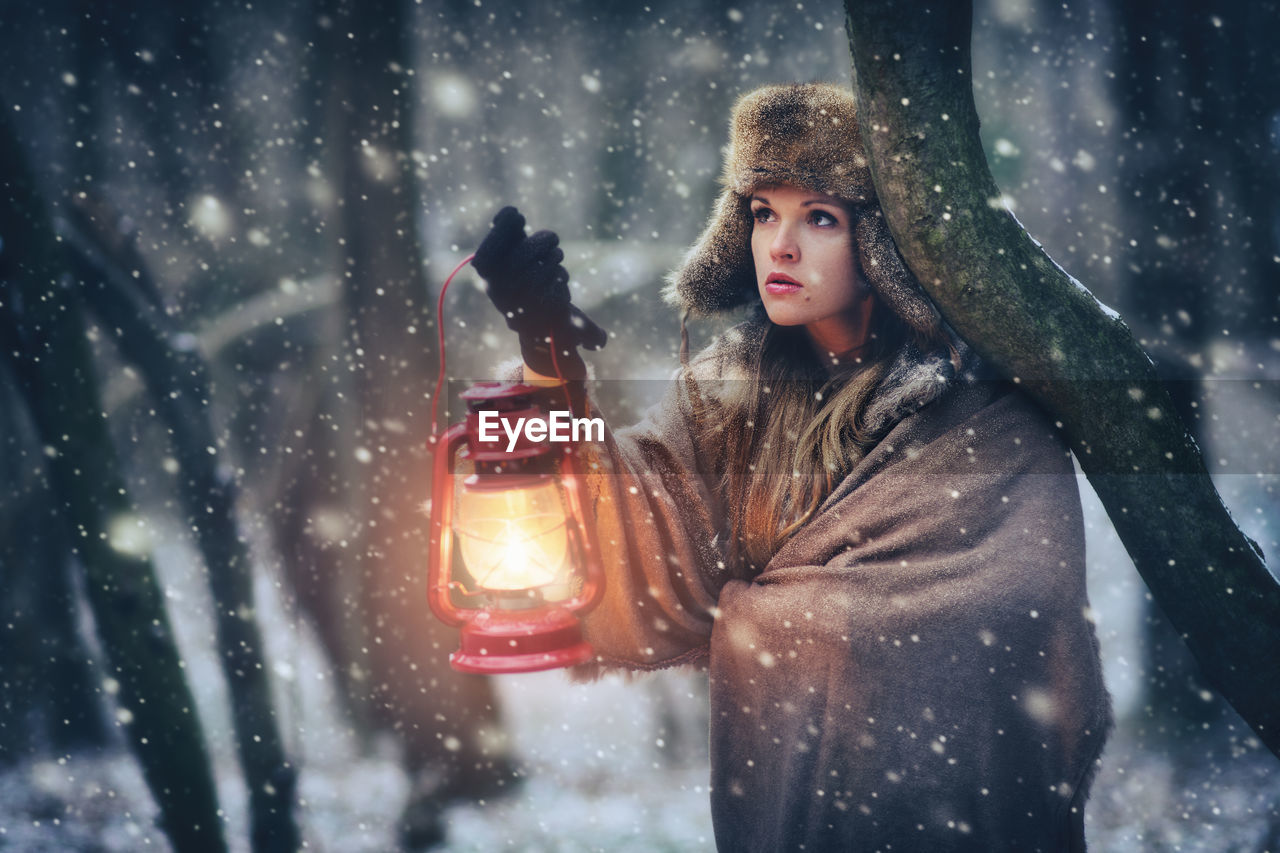 Portrait of young woman standing in snowfall