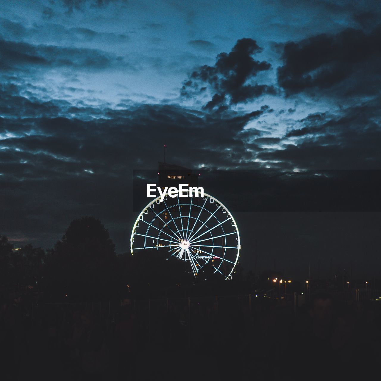 Illuminated ferris wheel against sky at night