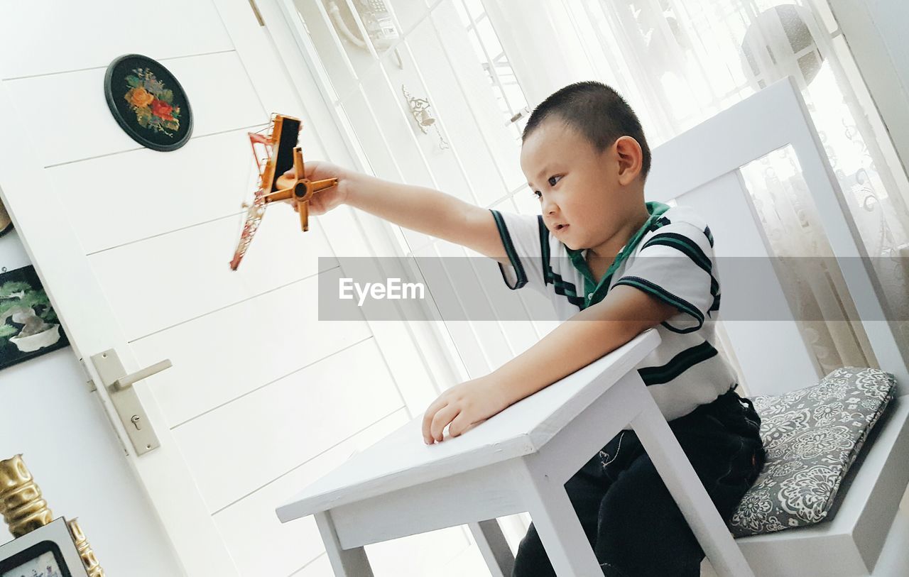 Boy playing with toy while sitting on chair