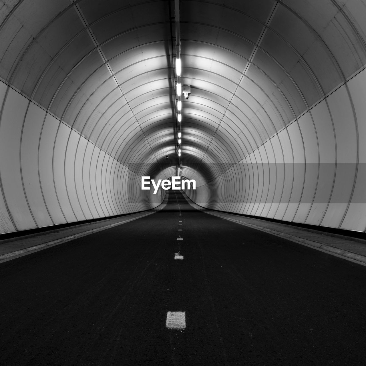 Illuminated empty road in tunnel