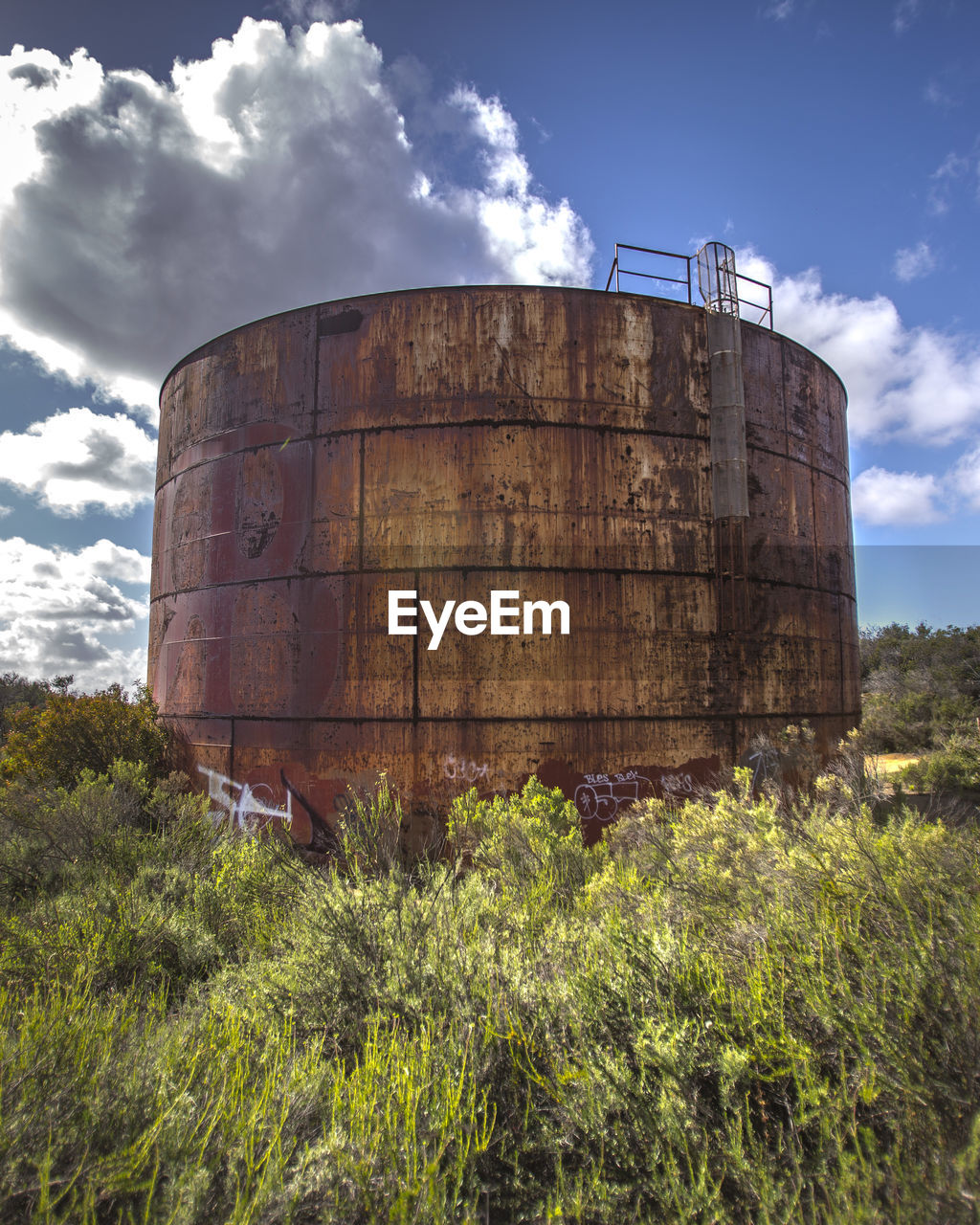 Storage tank against cloudy sky