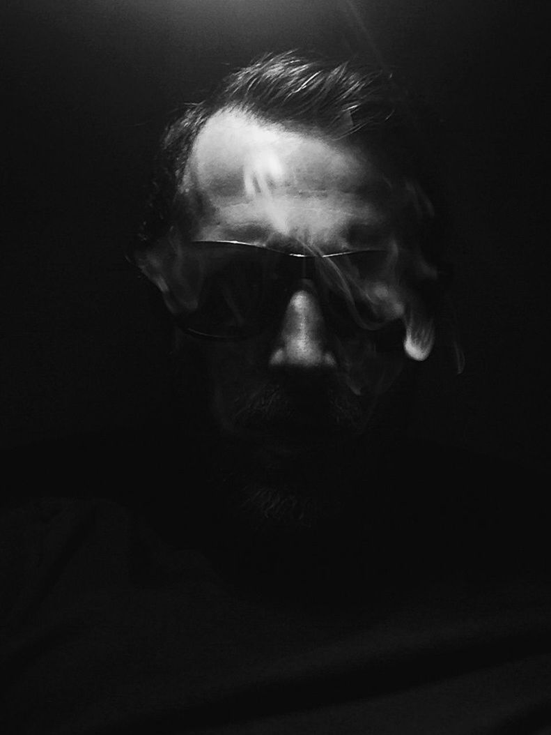Man surrounded by smokes in darkroom