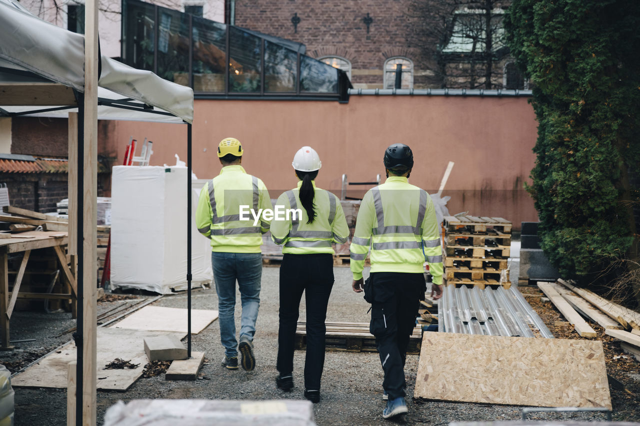 Rear view of male and female engineers walking at construction site
