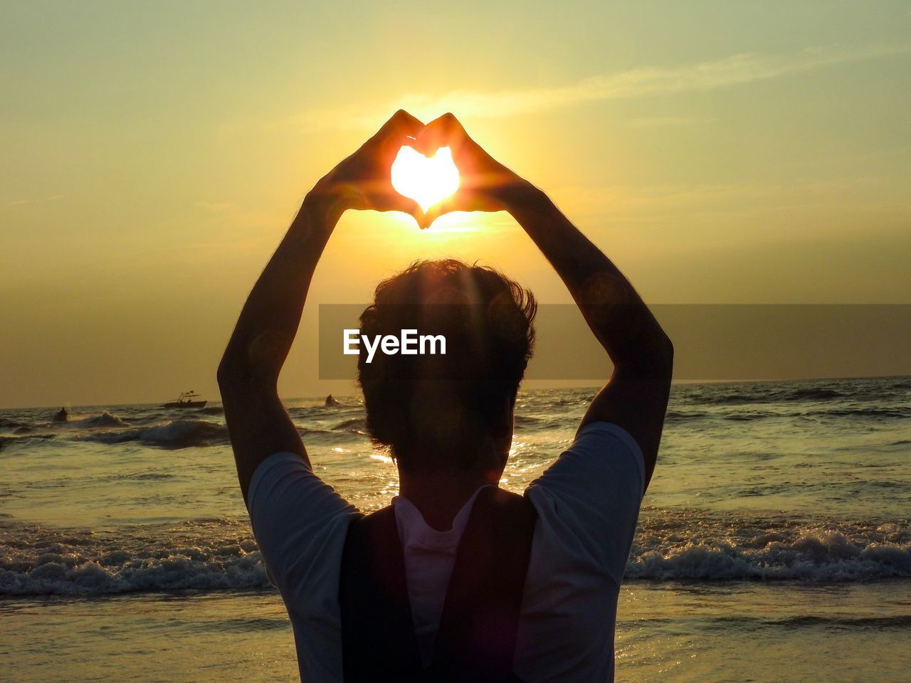 Young man at beach against sky during sunset