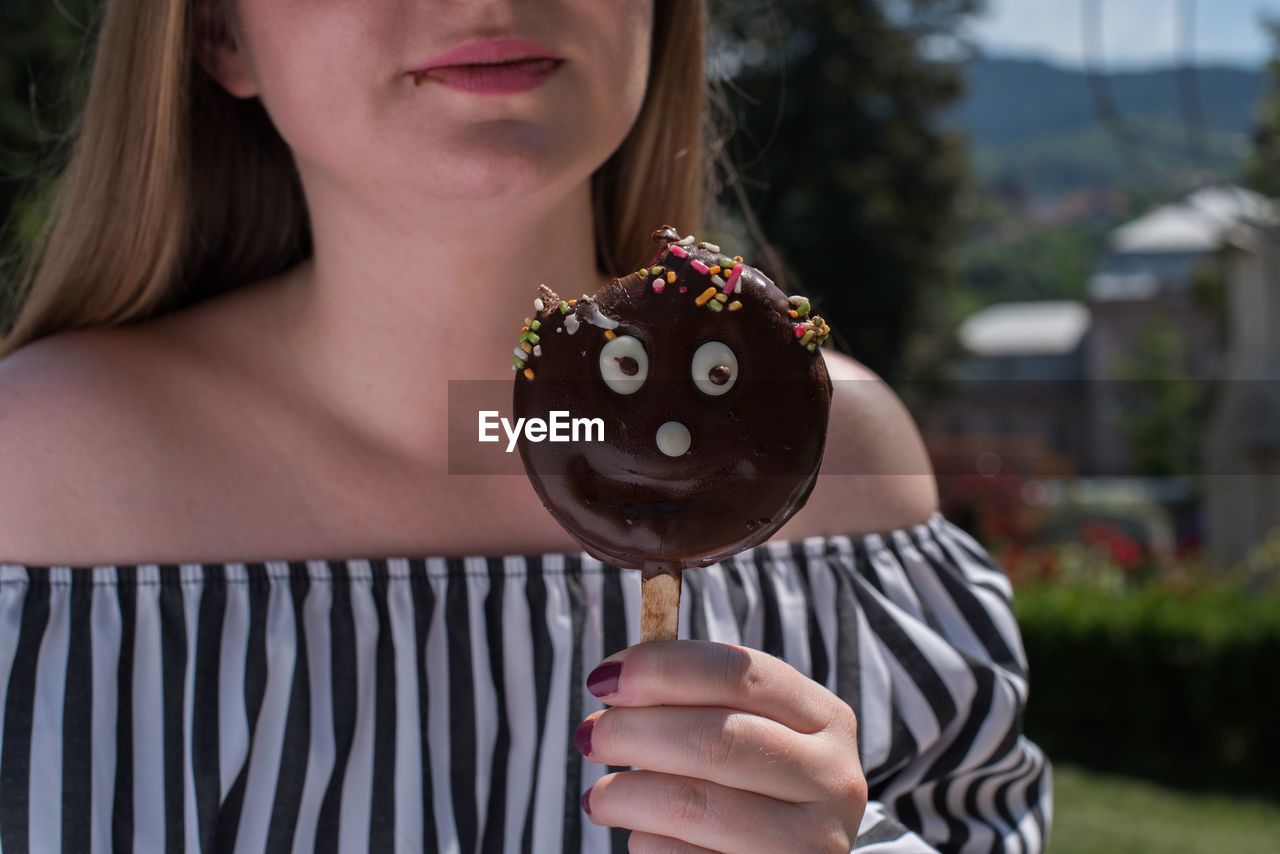 Midsection of woman eating chocolate candy during summer