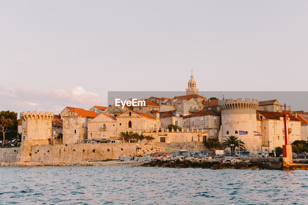 Buildings by sea against sky