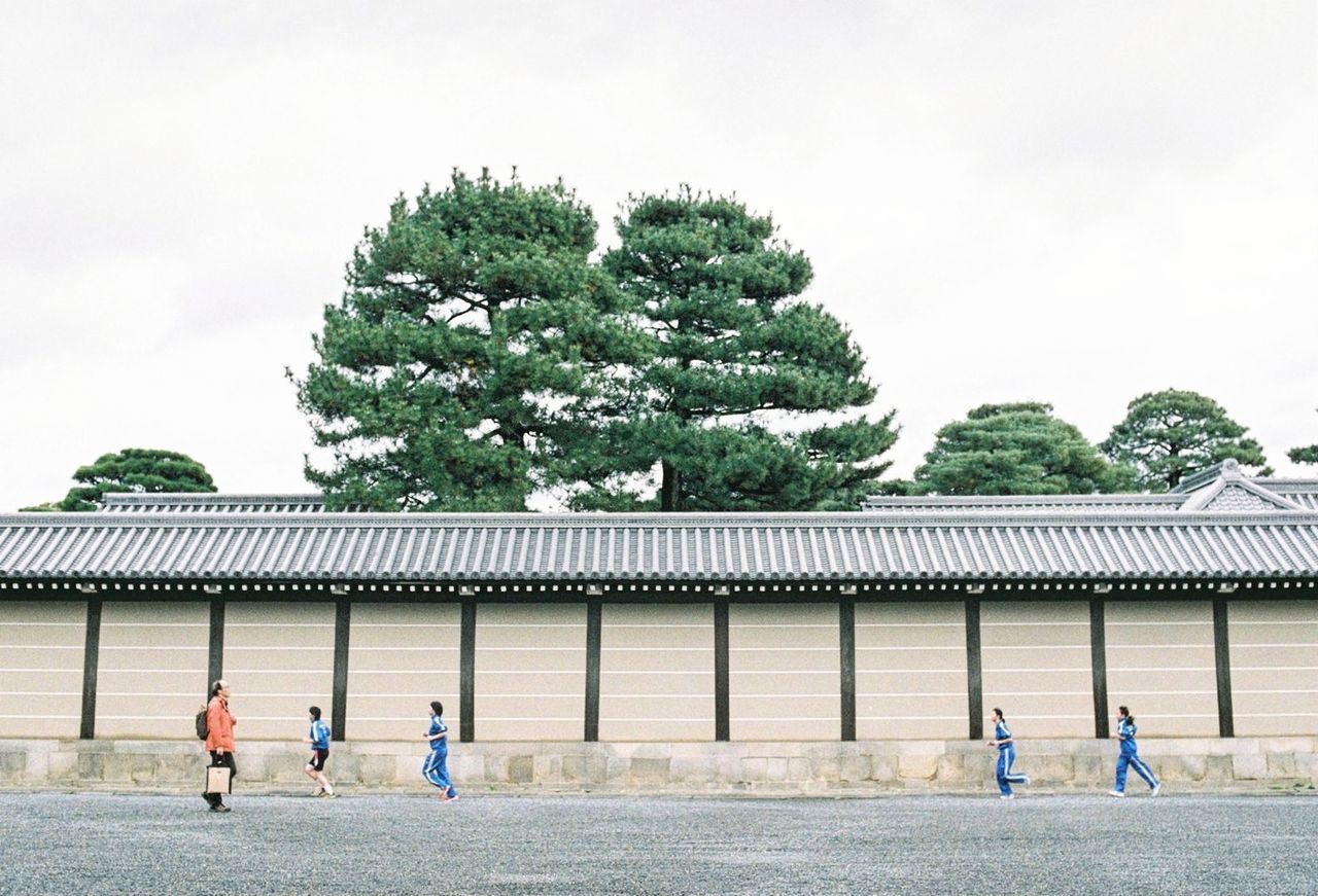 REAR VIEW OF PEOPLE WALKING BY BUILDING