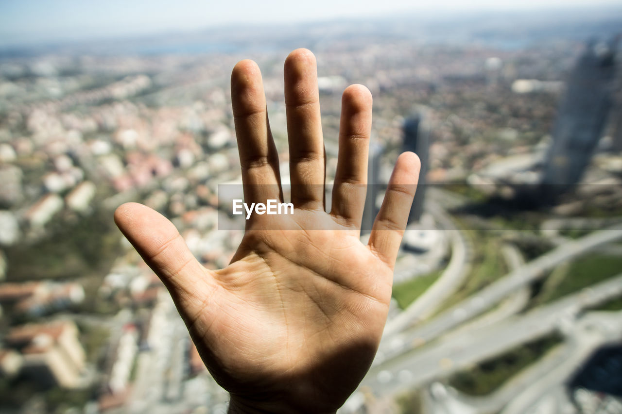 Close-up of human hand against cityscape