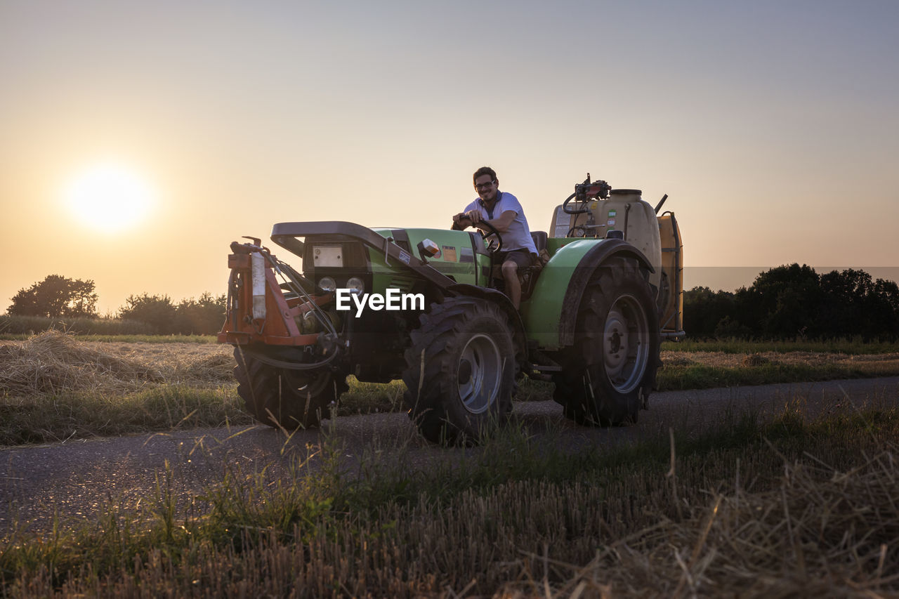 Organic farmer on a tractor at sunset