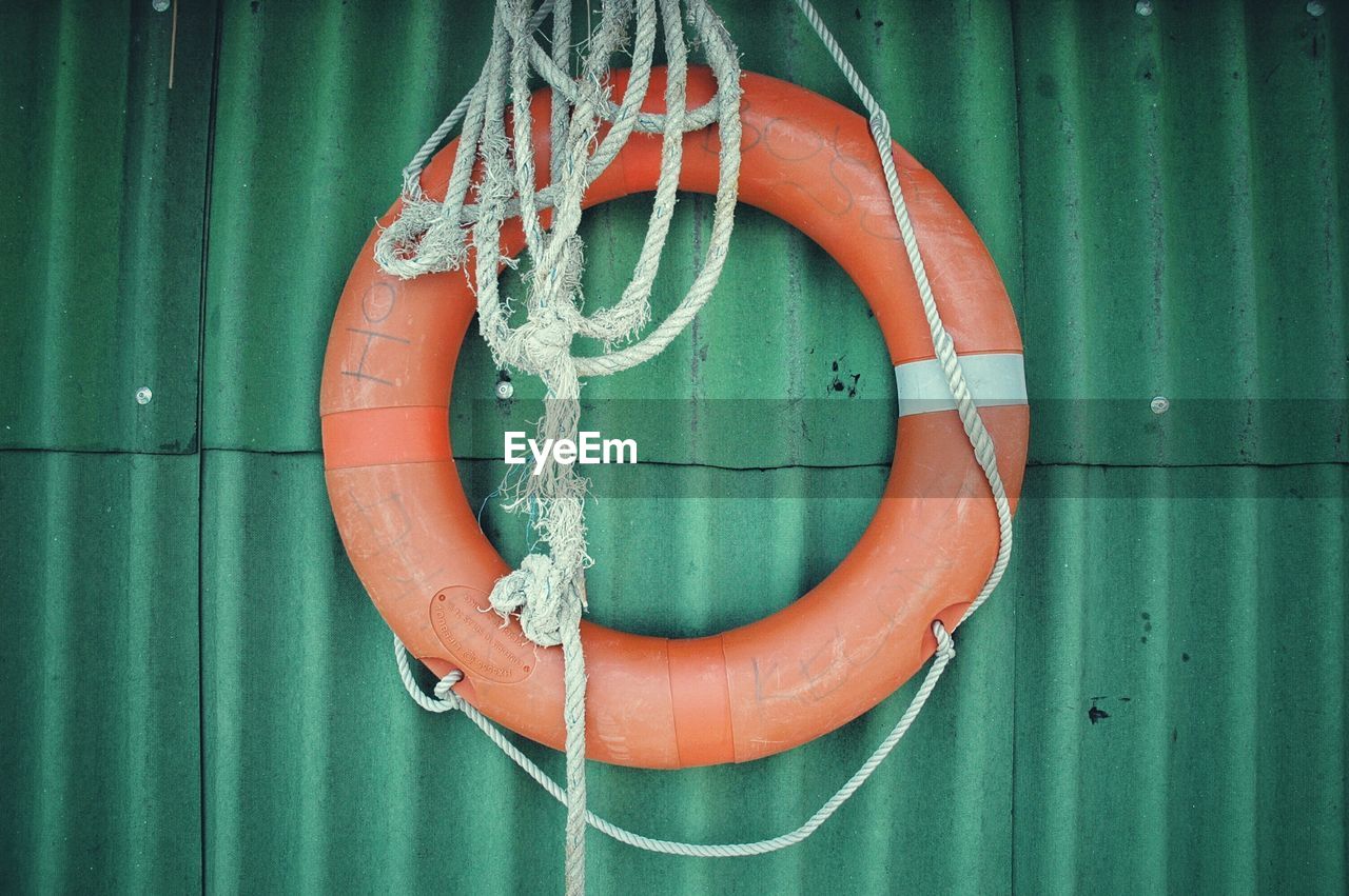 Life belt and rope hanging on green wall