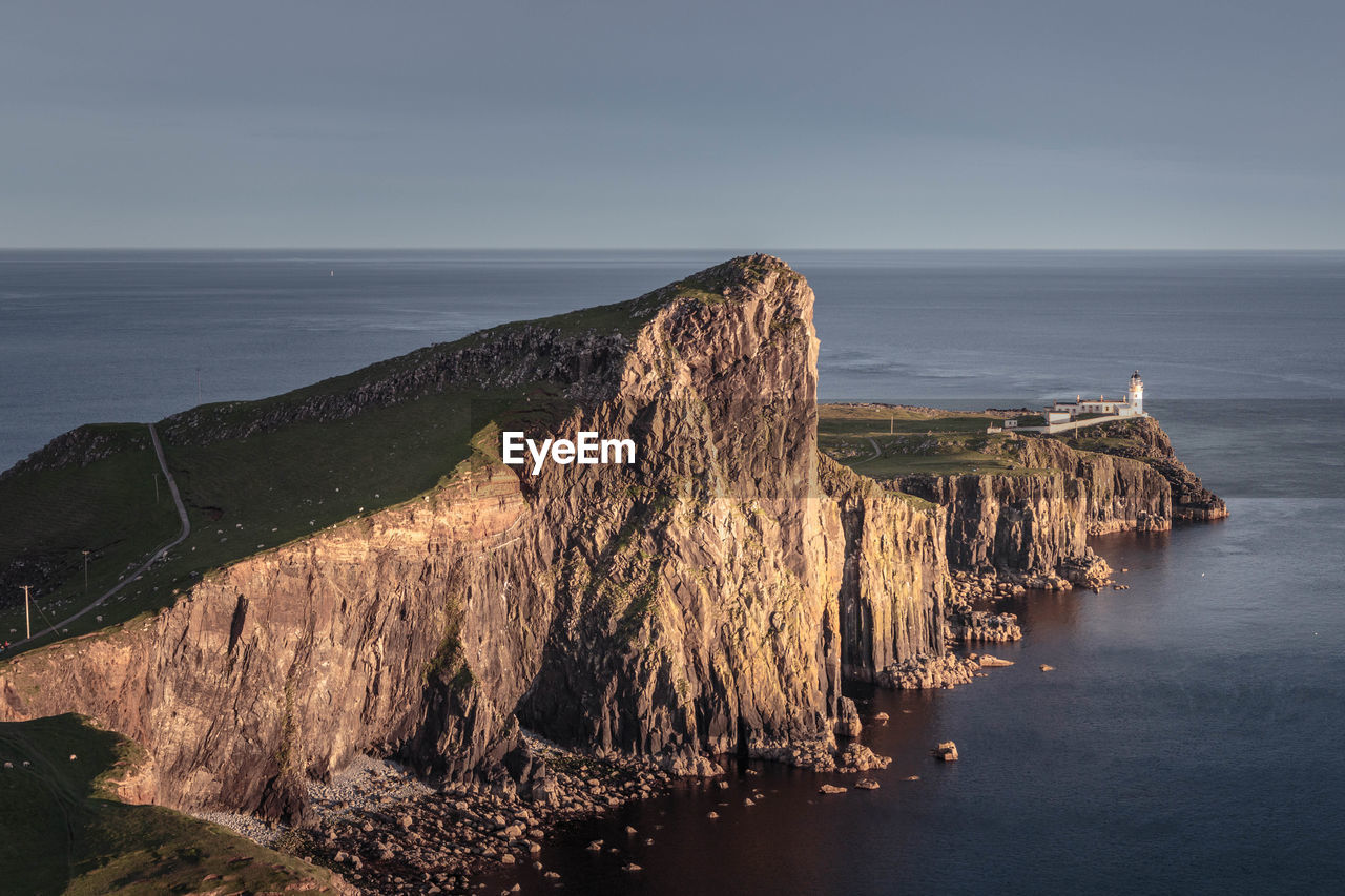 High angle view of cliff by sea against sky during sunset