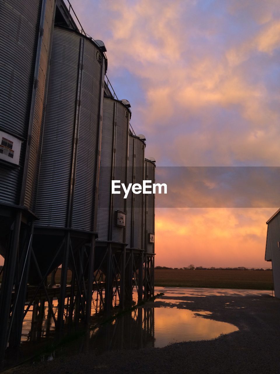 Low angle view of cropped silos against clouds