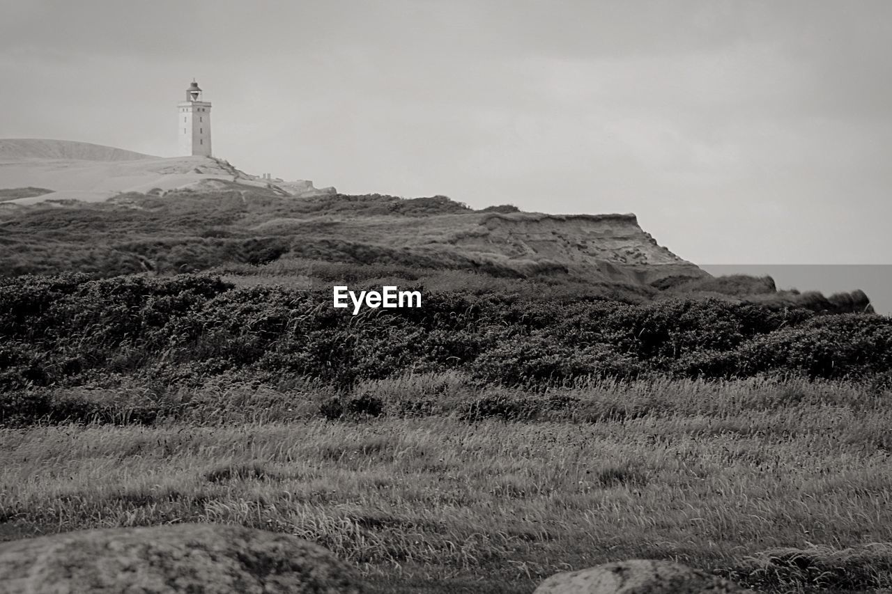 Lighthouse on landscape against sky