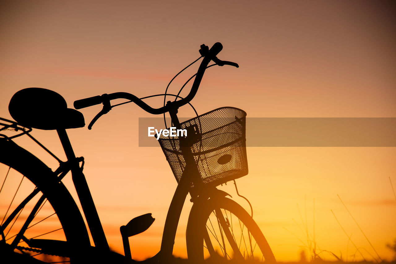 SILHOUETTE OF BICYCLES AGAINST ORANGE SKY