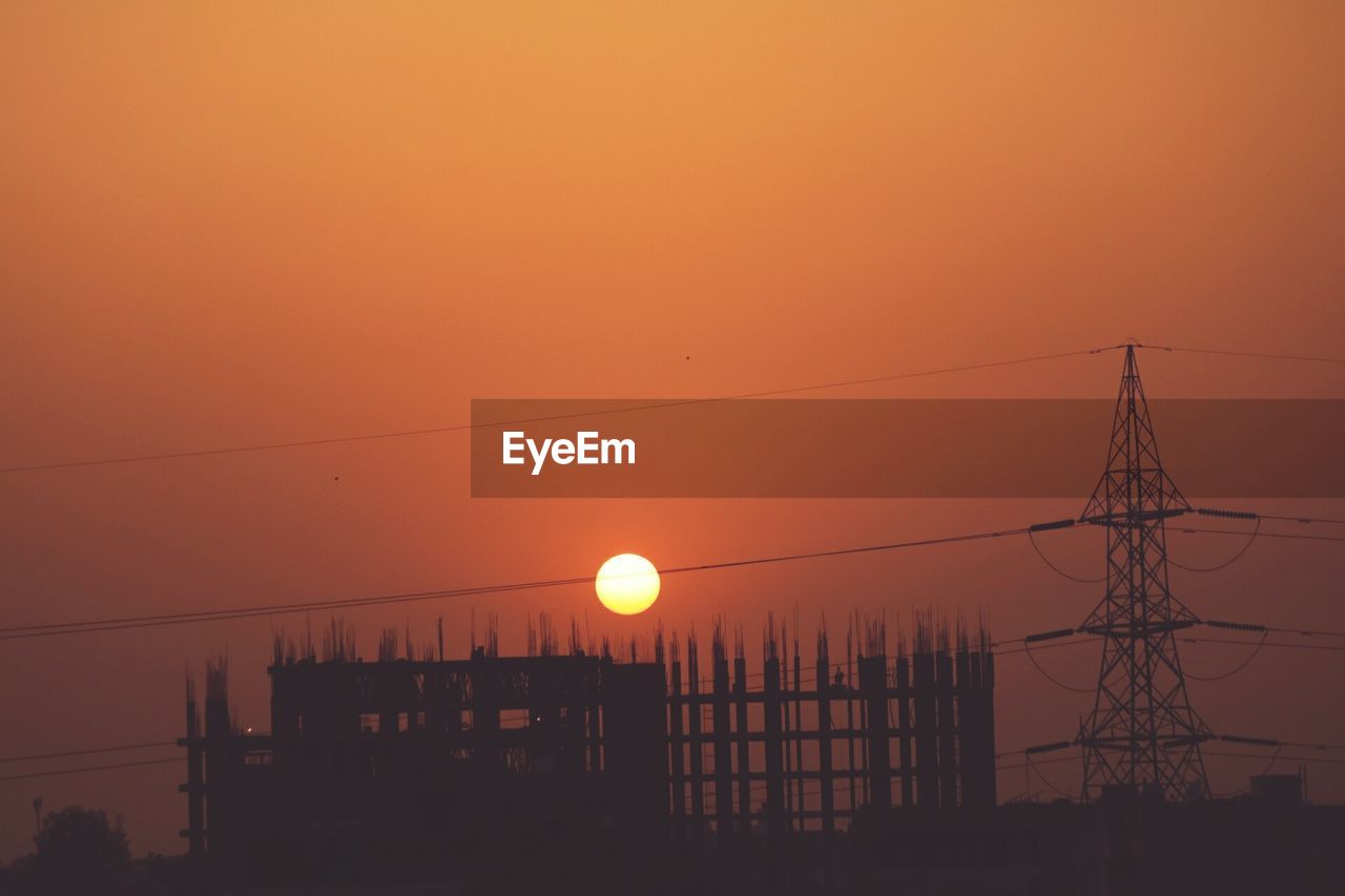 Low angle view of power lines against sky at sunset