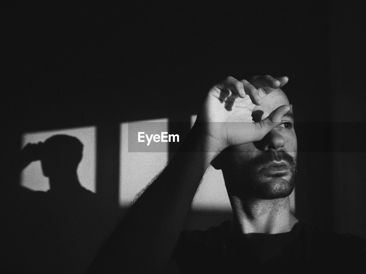 Man looking away while sitting in darkroom