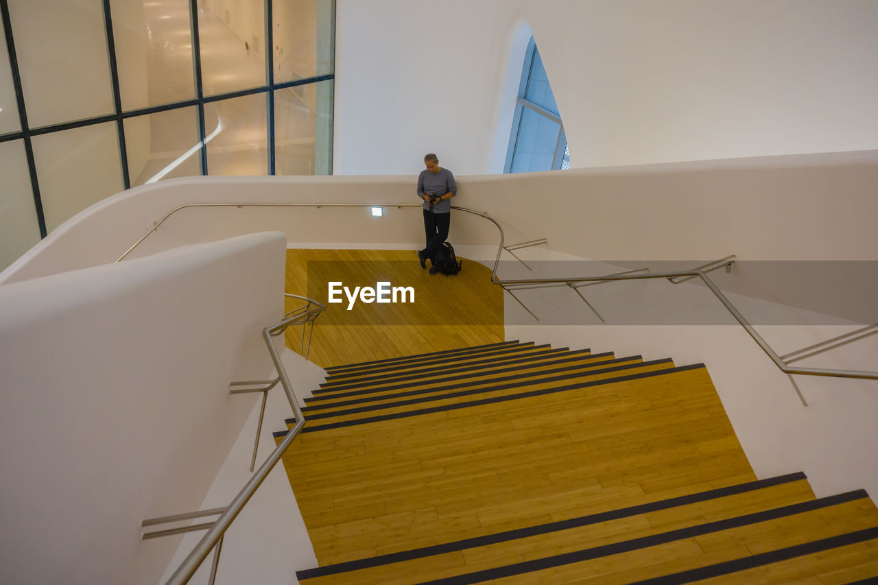 REAR VIEW OF MAN STANDING BY STAIRCASE IN BUILDING