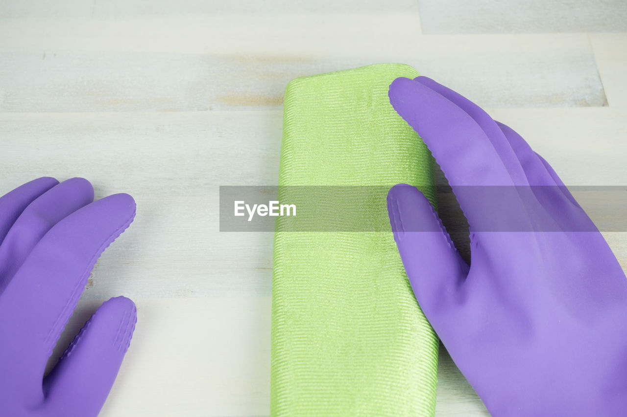 Close-up of person wearing gloves while cleaning floor