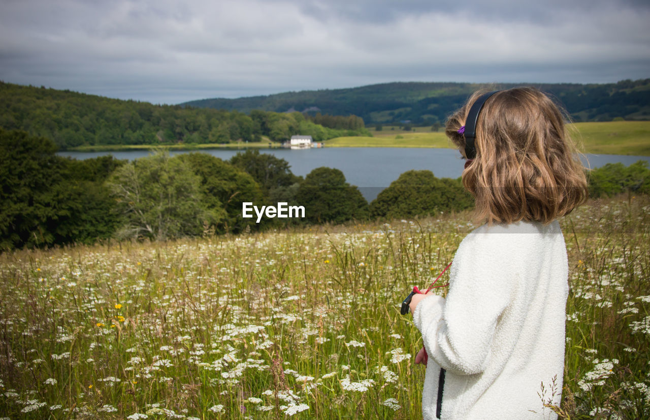 Girl looking at field against sky