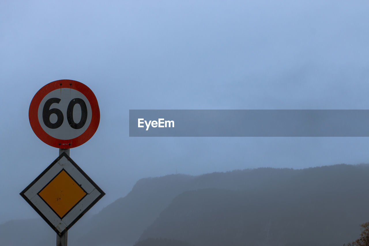 LOW ANGLE VIEW OF ROAD SIGN AGAINST MOUNTAIN