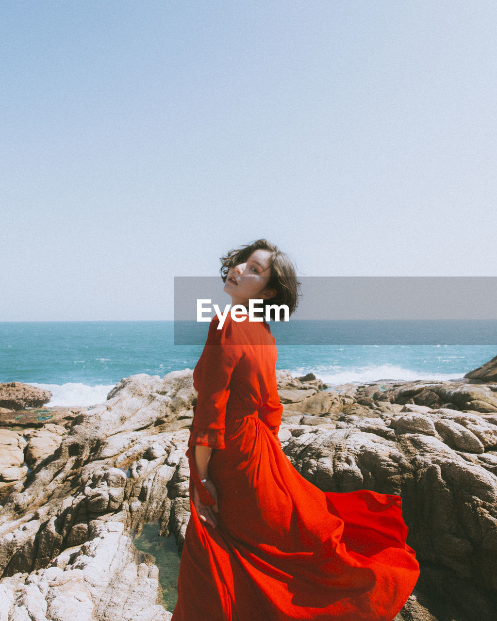 Young woman at beach against sky