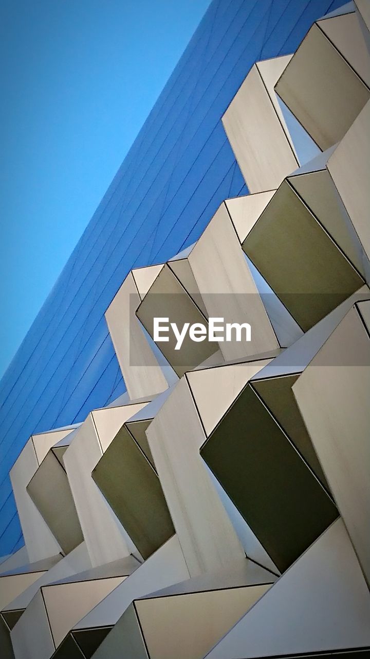 DIRECTLY BELOW SHOT OF MODERN BUILDING AGAINST CLEAR BLUE SKY