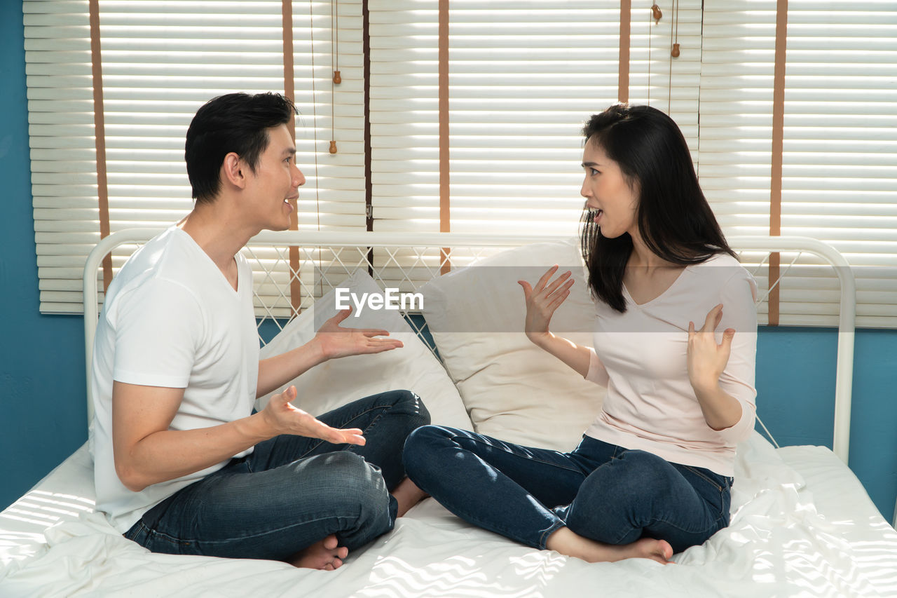Unhappy couple sitting beside each other on the floor and avoid talking