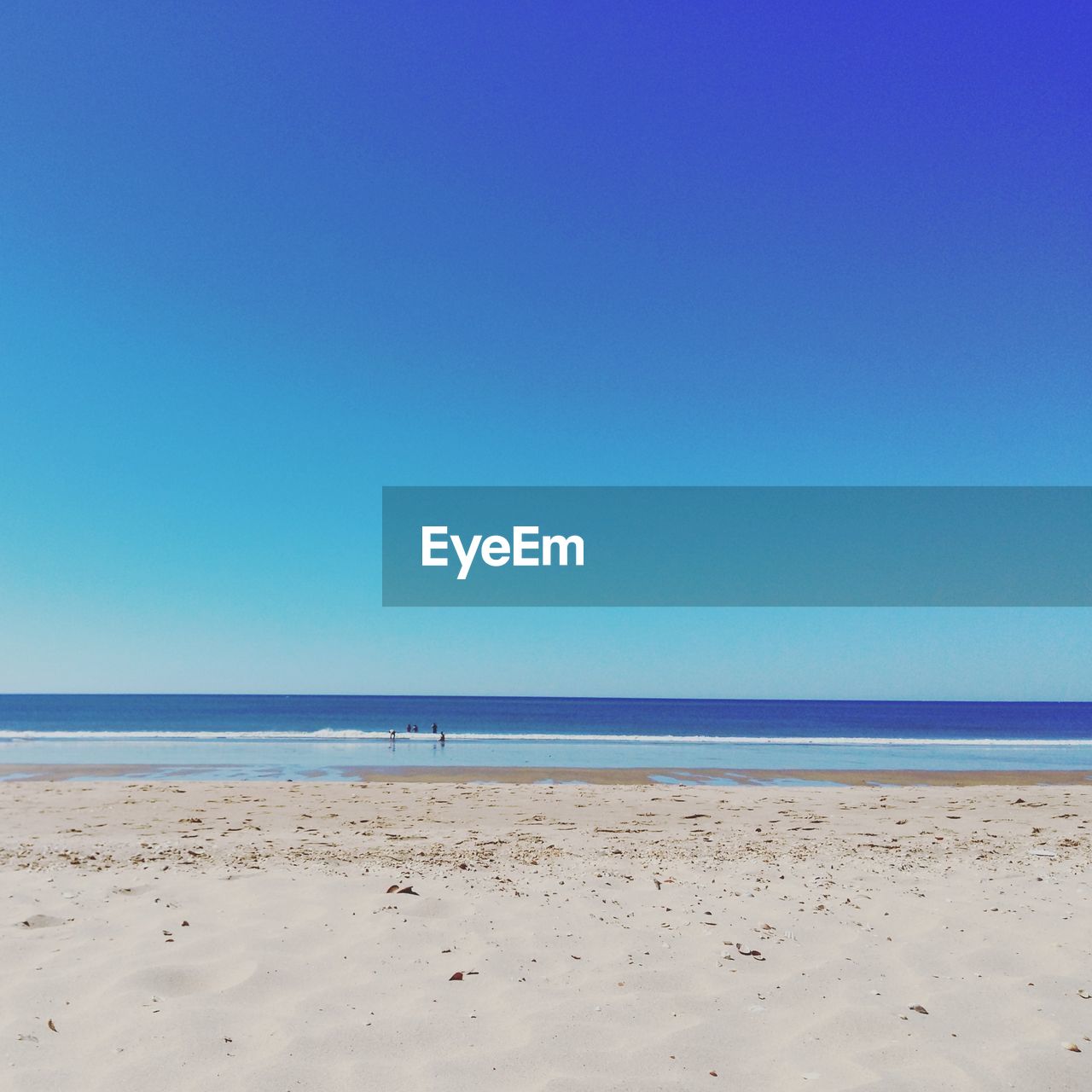 Scenic view of calm beach against blue sky