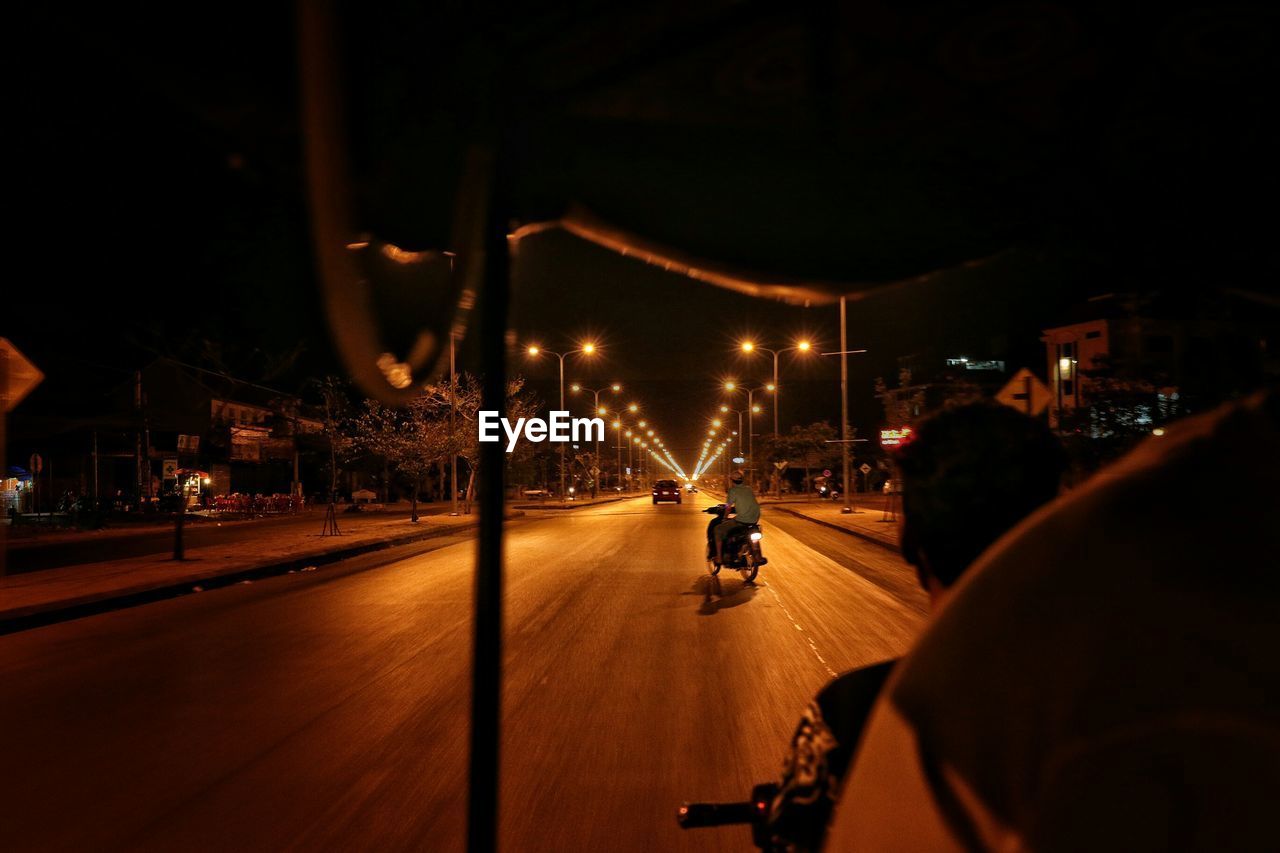 Empty road along lit street lights at night