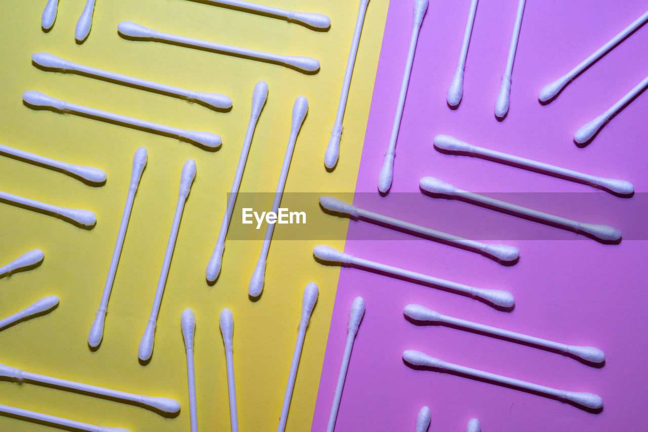 Cotton swabs on a pink and yellow background.