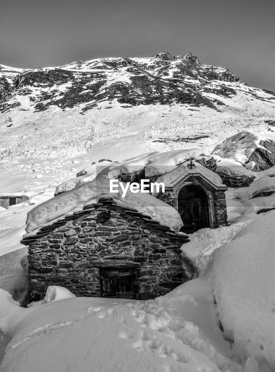 Snow covered houses by building against sky