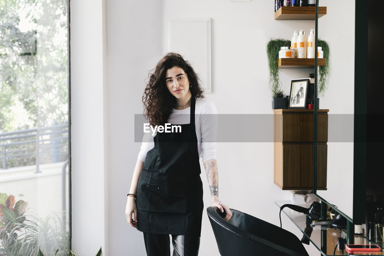 Portrait of female owner standing in hair salon