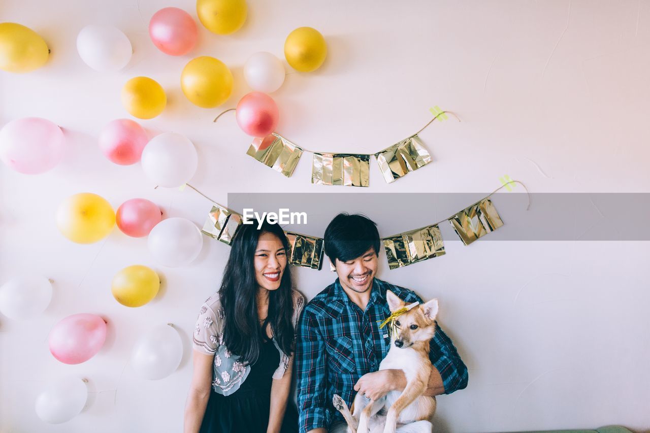 Smiling couple with dog against decorated wall