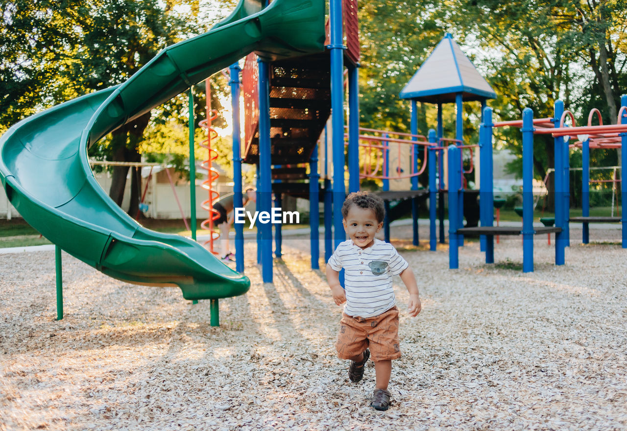 Diverse mixed race toddler boy at playground park having fun making childhood memories