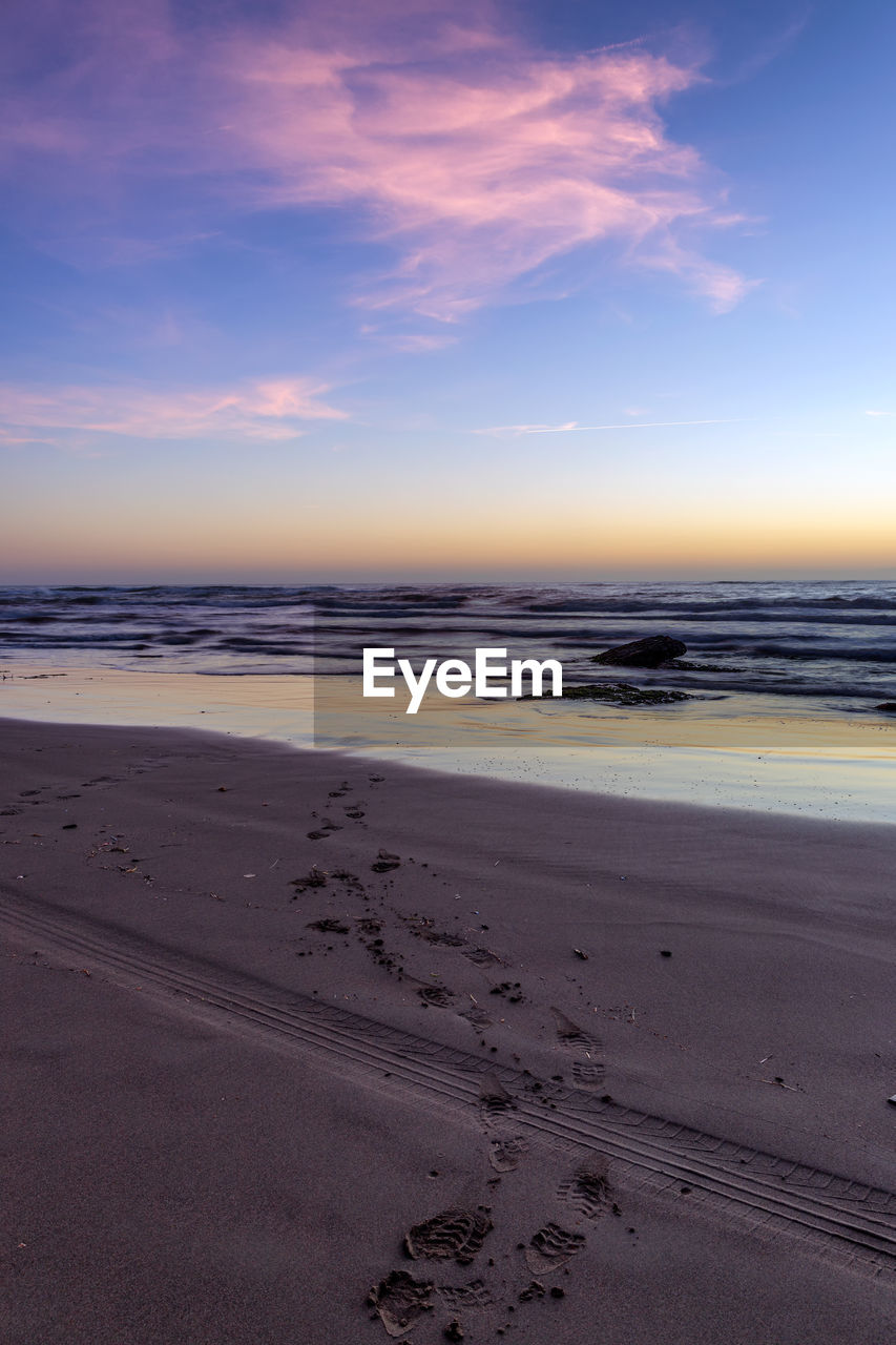 SCENIC VIEW OF BEACH AGAINST SKY AT SUNSET