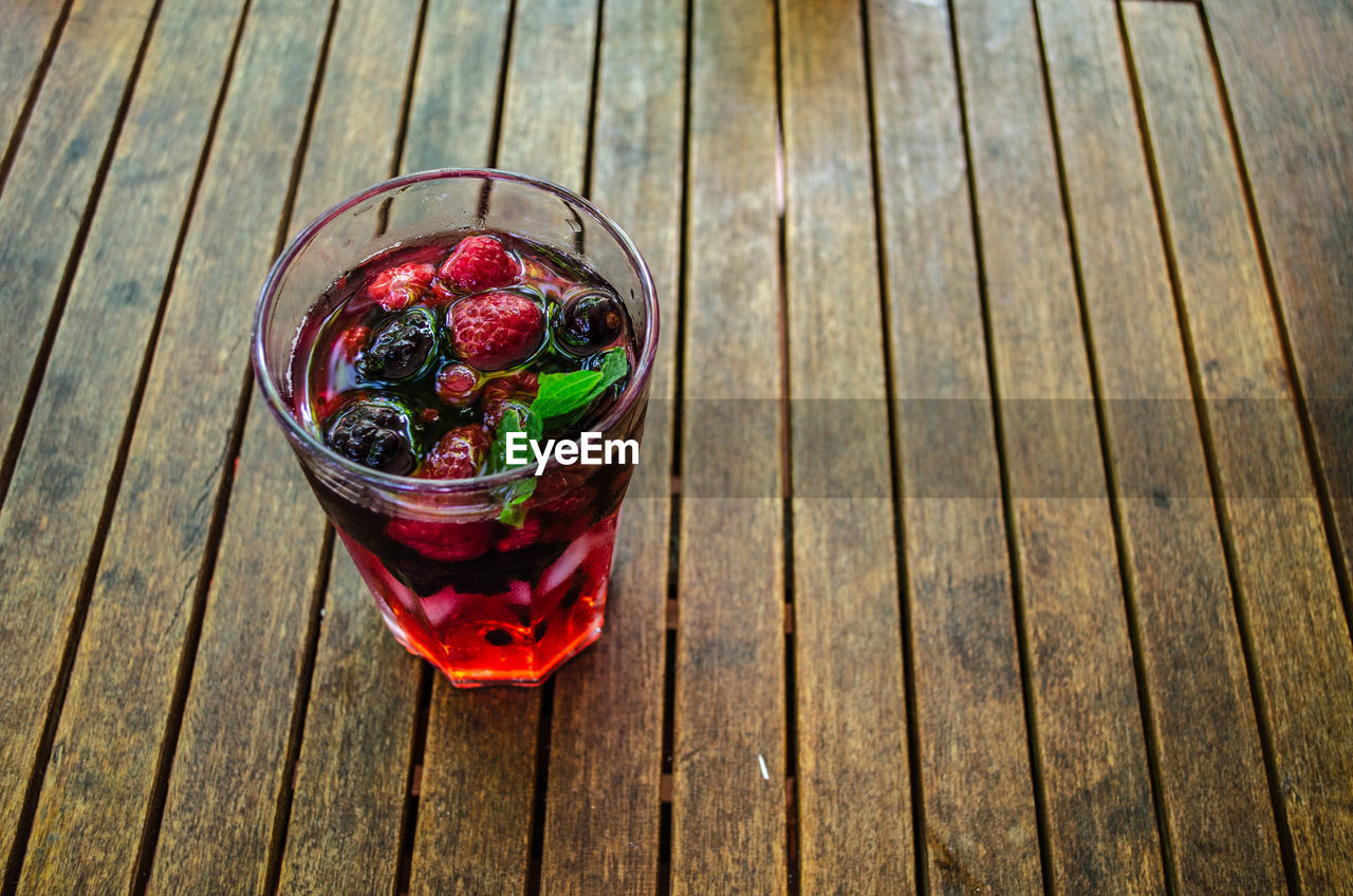 Directly above shot of glass with raspberry on wooden table