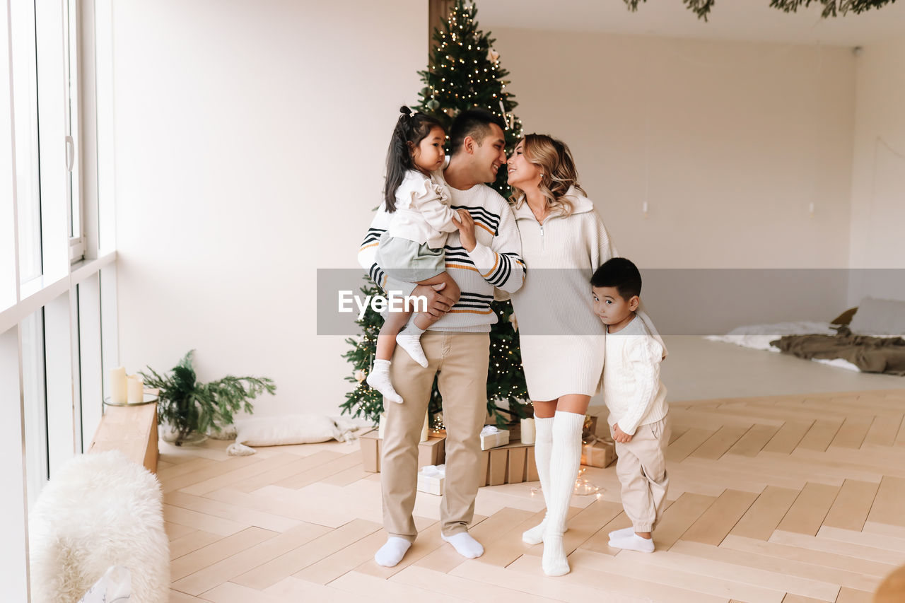 An asian multi-racial family with two children celebrate the christmas holiday in a decorated house