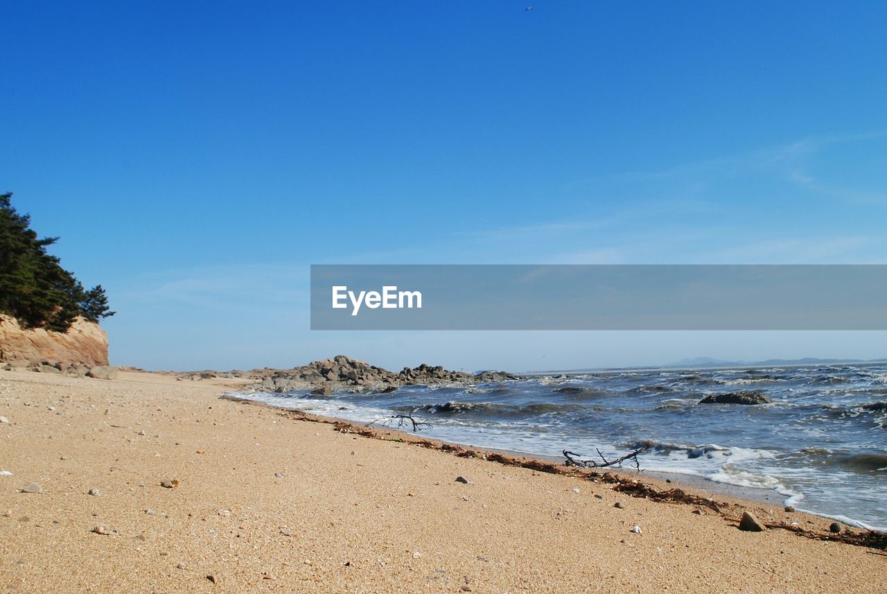 Scenic view of beach against blue sky