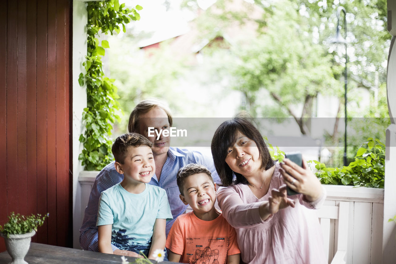 Mother taking selfie with family in porch