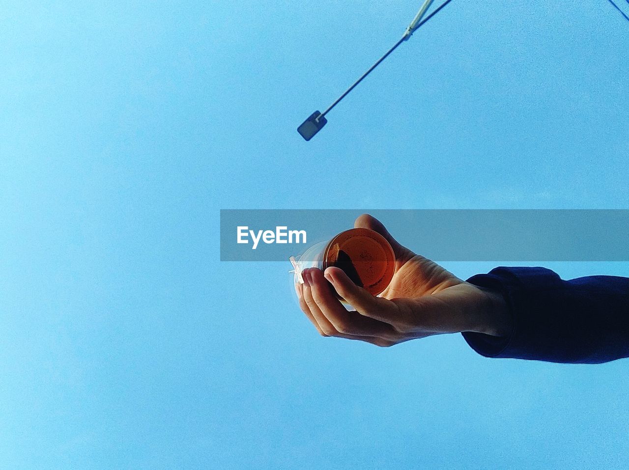 Low angle view of person hand against blue sky