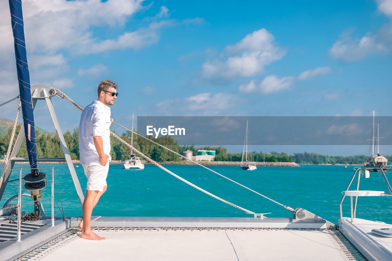 Man standing in boat on sea against sky