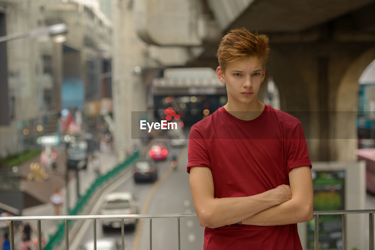 Young man standing against road in city