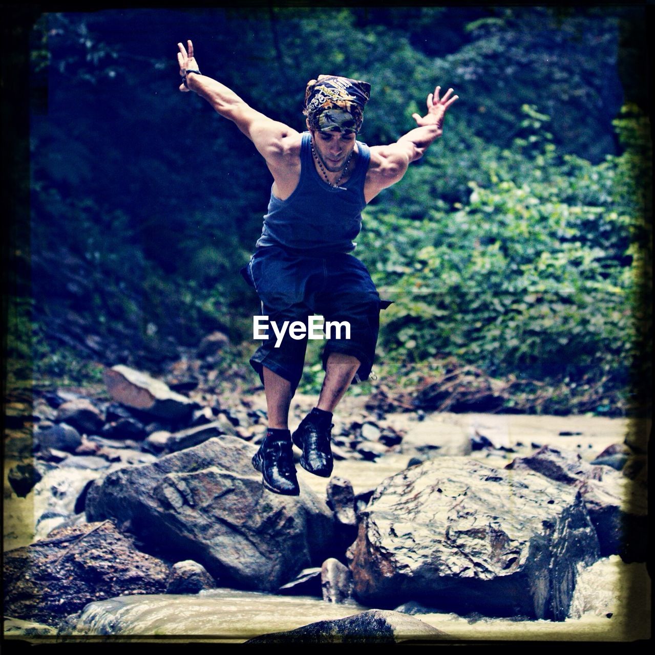 Young man jumping over stream