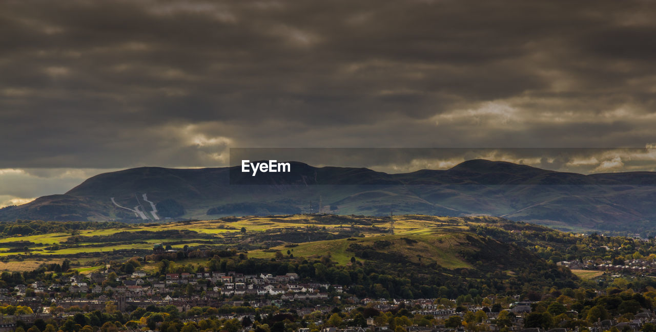 Scenic view of landscape against cloudy sky during sunset