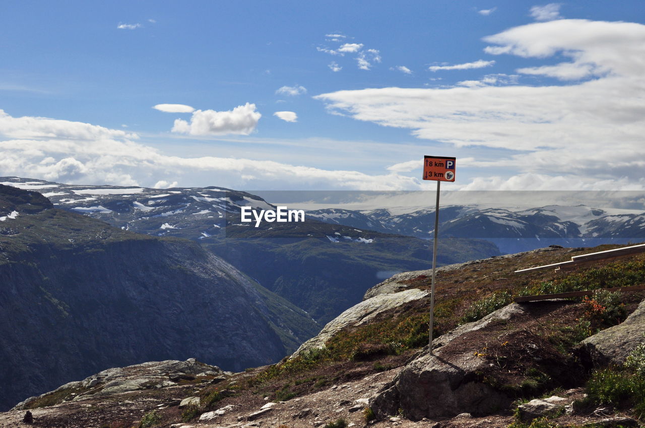 Information sign on mountain against cloudy sky during sunny day