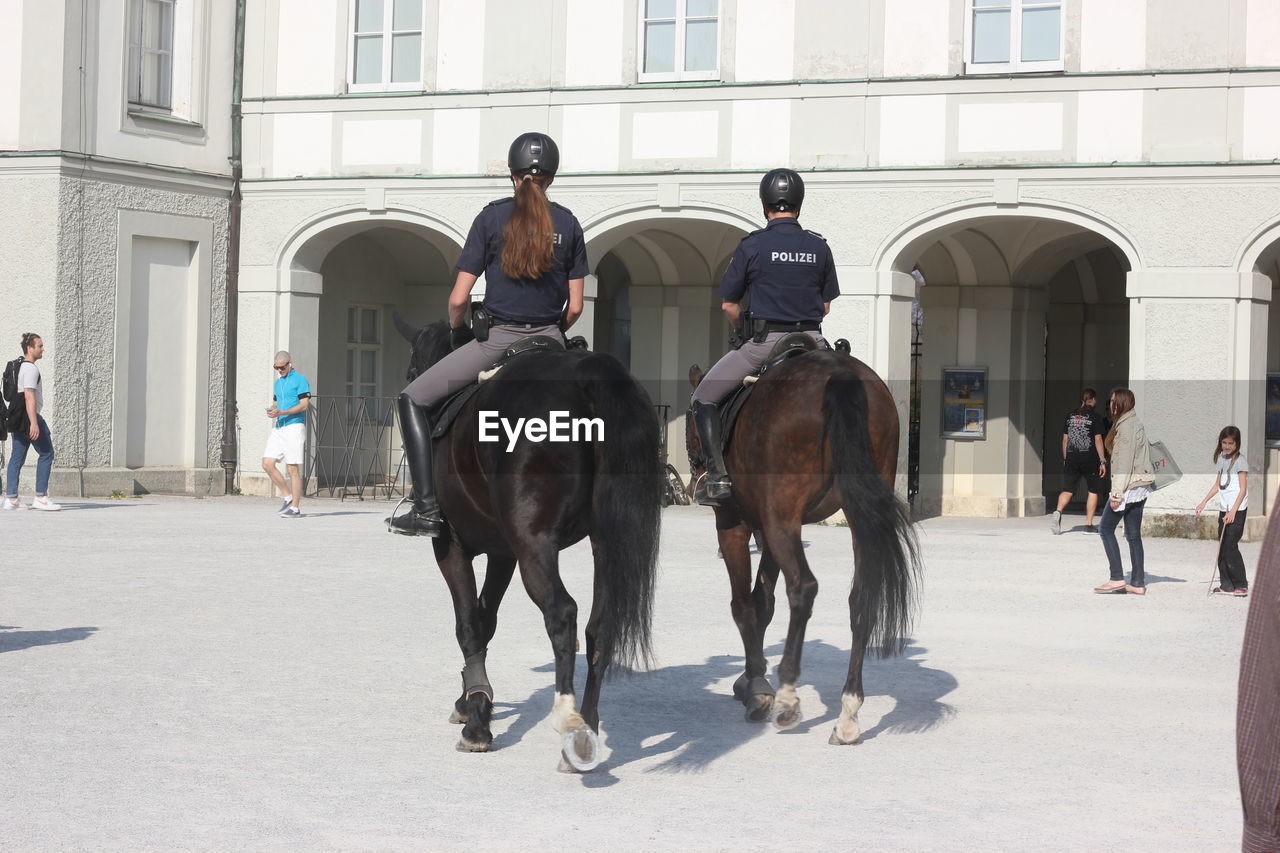 PEOPLE RIDING HORSES ON STREET