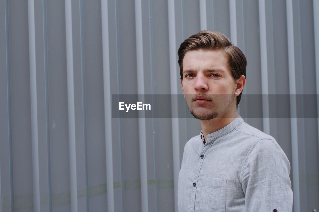 Front view of handsome man standing against wall